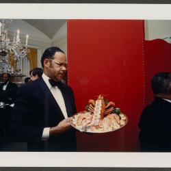 John H. Johnson carries a tray of "lobster en bellevue" from the Family Dining Room to the State Dining Room to serve them guests at a State Dinner hosted by President Gerald R.  Ford in honor of Emperor Hirohito of Japan on October 2, 1975.